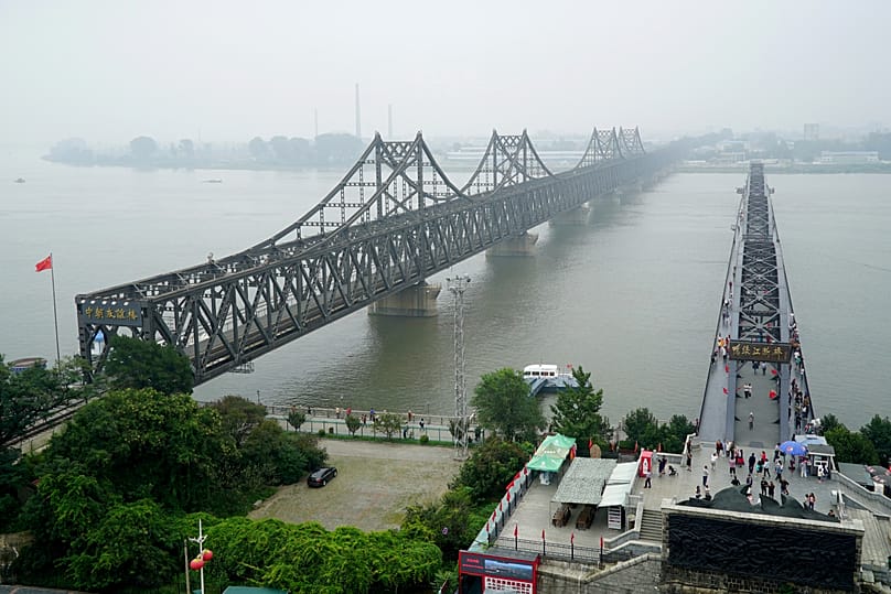 Visitors walk across the Yalu River Broken Bridge next to the Friendship Bridge connecting China and North Korea in Liaoning province, 9 September, 2017