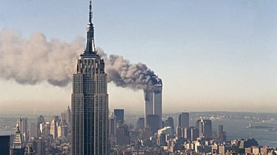 Οι δίδυμοι πύργοι του Παγκόσμιου Κέντρου Εμπορίου καίγονται πίσω από το Εμπάιρ Στέιτ Μπίλντινγκ στη Νέα Υόρκη, 11 Σεπτεμβρίου 2001
