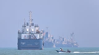 FILE: A small motorboat passes anchored vessels in the Strait of Hormuz off Bandar Abbas, Iran, 11 June 2026