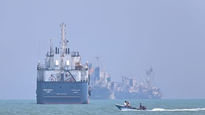FILE: A small motorboat passes anchored vessels in the Strait of Hormuz off Bandar Abbas, Iran, 11 June 2026