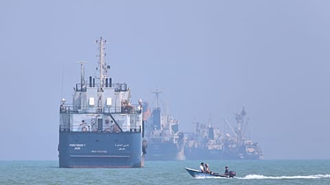 FILE: A small motorboat passes anchored vessels in the Strait of Hormuz off Bandar Abbas, Iran, 11 June 2026