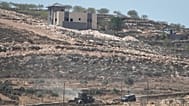 Israeli army vehicles operate near Palestinian houses, besieged by Israeli settlers, in the occupied West Bank village of Qusra, south of Nablus, Thursday, Aug. 13, 2026.