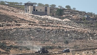 Israeli army vehicles operate near Palestinian houses, besieged by Israeli settlers, in the occupied West Bank village of Qusra, south of Nablus, Thursday, Aug. 13, 2026.