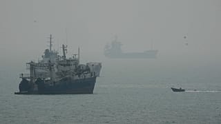 A motorboat travels past commercial vessels anchored amid haze in the Strait of Hormuz off Bandar Abbas, Iran, Monday, Sept. 7, 2026.