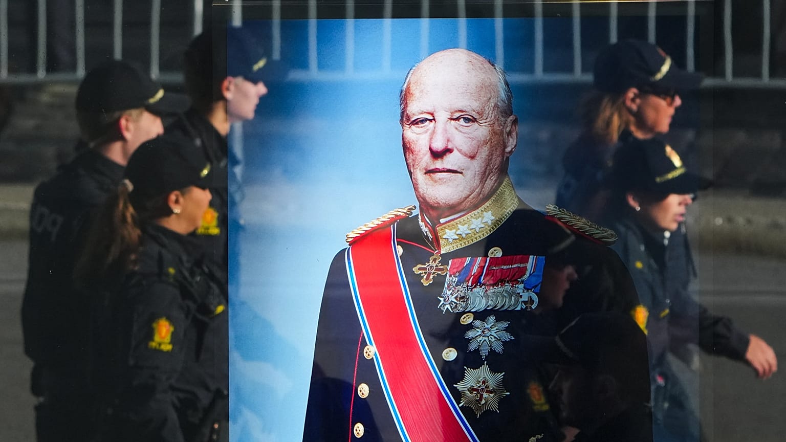 Police officers reflected in a window with a display showing Norway's late King Harald V prior to his funeral in Oslo, 9 September, 2026