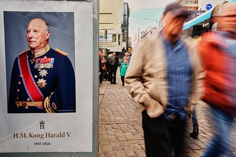 People walk past a poster depicting Norway's late King Harald on the eve of his funeral in Oslo, 8 September, 2026