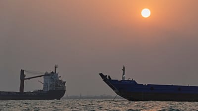 FILE. The sun sets over commercial vessels anchored in the Strait of Hormuz off Bandar Abbas, Iran, 6 Sept. 2026