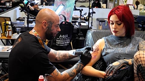 Tattoo artist Thiago Miranda tattooing a woman's arm