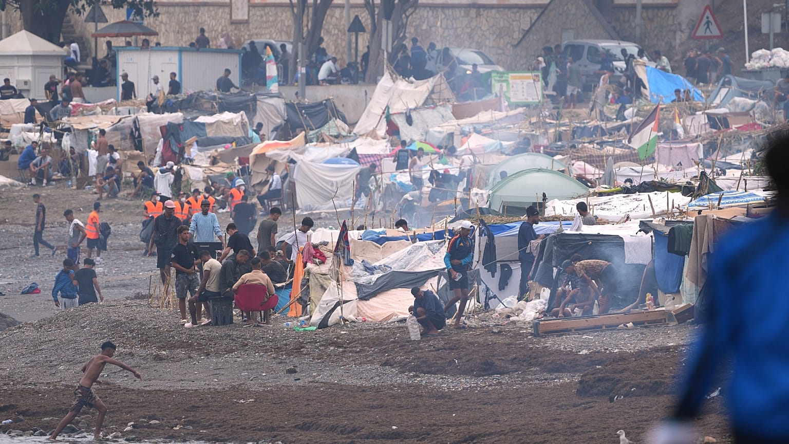 Migrants stand near their tents at El Trampolín beach in the Spanish exclave of Ceuta