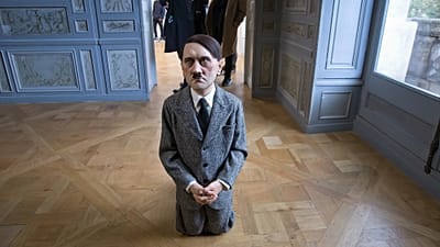 Ziyaretçiler, Maurizio Cattelan’ın Adolf Hitler’i tasvir eden tartışmalı “o” adlı heykel yerleştirmesini inceliyor.