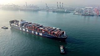 Schlepper manövrieren ein Containerschiff der Reederei CMA CGM nahe einem Hafen in Qingdao in der ostchinesischen Provinz Shandong, am 30. November 2025.