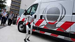 A humanoid robot walks by Japan's mobile maintenance unit for humanoid robots during a news conference by GMO, a Japanese internet infrastructure company, Tuesday, Sept. 8,