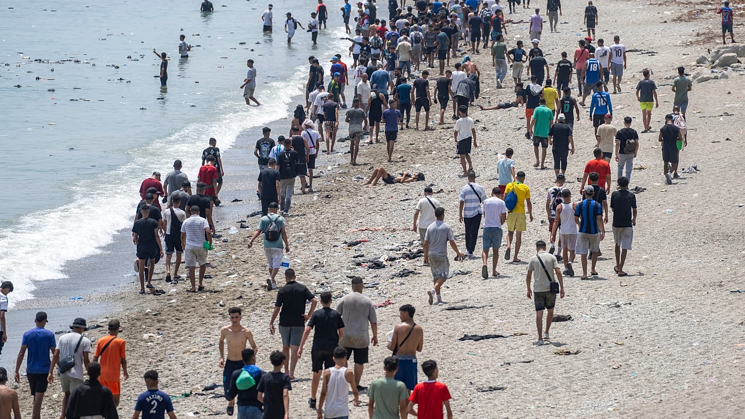 Άνθρωποι περπατούν σε παραλία μετά την προσπάθεια να περάσουν από τη μαροκινή πόλη Φνιντέκ, στο βόρειο Μαρόκο, προς τον ισπανικό θύλακα Θέουτα στις 31 Ιουλίου 2026