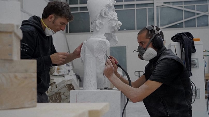 Los trabajadores utilizan herramientas tradicionales para finalizar una escultura de mármol en Carrara, Italia.