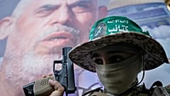 يحمل صبي فلسطيني مسدساً نُقشت عليه كلمة "حماس" باللغة العربية، ويقف أمام صورة للقيادي الراحل في حركة حماس يحيى السنوار، 