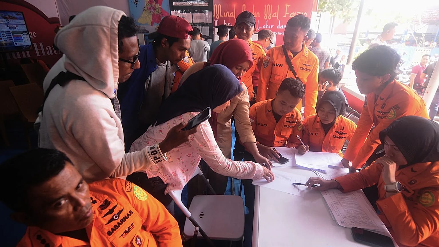 People look for the names of their family members on a passenger list after a ferry overturned in bad weather in the Java Sea, at the rescuers command center in Banjarmasin.
