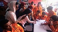 People look for the names of their family members on a passenger list after a ferry overturned in bad weather in the Java Sea, at the rescuers command center in Banjarmasin.