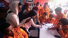 People look for the names of their family members on a passenger list after a ferry overturned in bad weather in the Java Sea, at the rescuers command center in Banjarmasin.