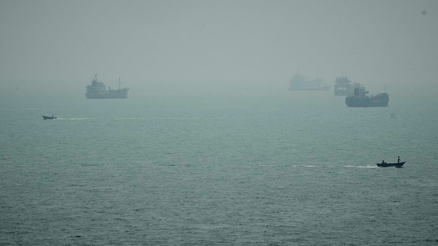 Motorboats travel past commercial vessels anchored amid haze in the Strait of Hormuz off Bandar Abbas, Iran, Monday, Sept. 7, 2026.