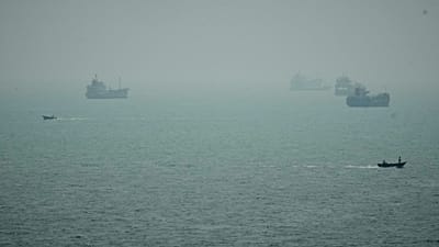Motorboats travel past commercial vessels anchored amid haze in the Strait of Hormuz off Bandar Abbas, Iran, Monday, Sept. 7, 2026.