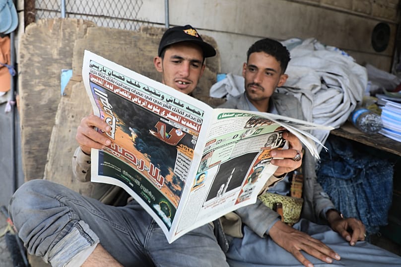 ARCHIV: Menschen verfolgen in einem Laden in Sanaa am 8. September 2026 die Kriegsnachrichten in einer Zeitung