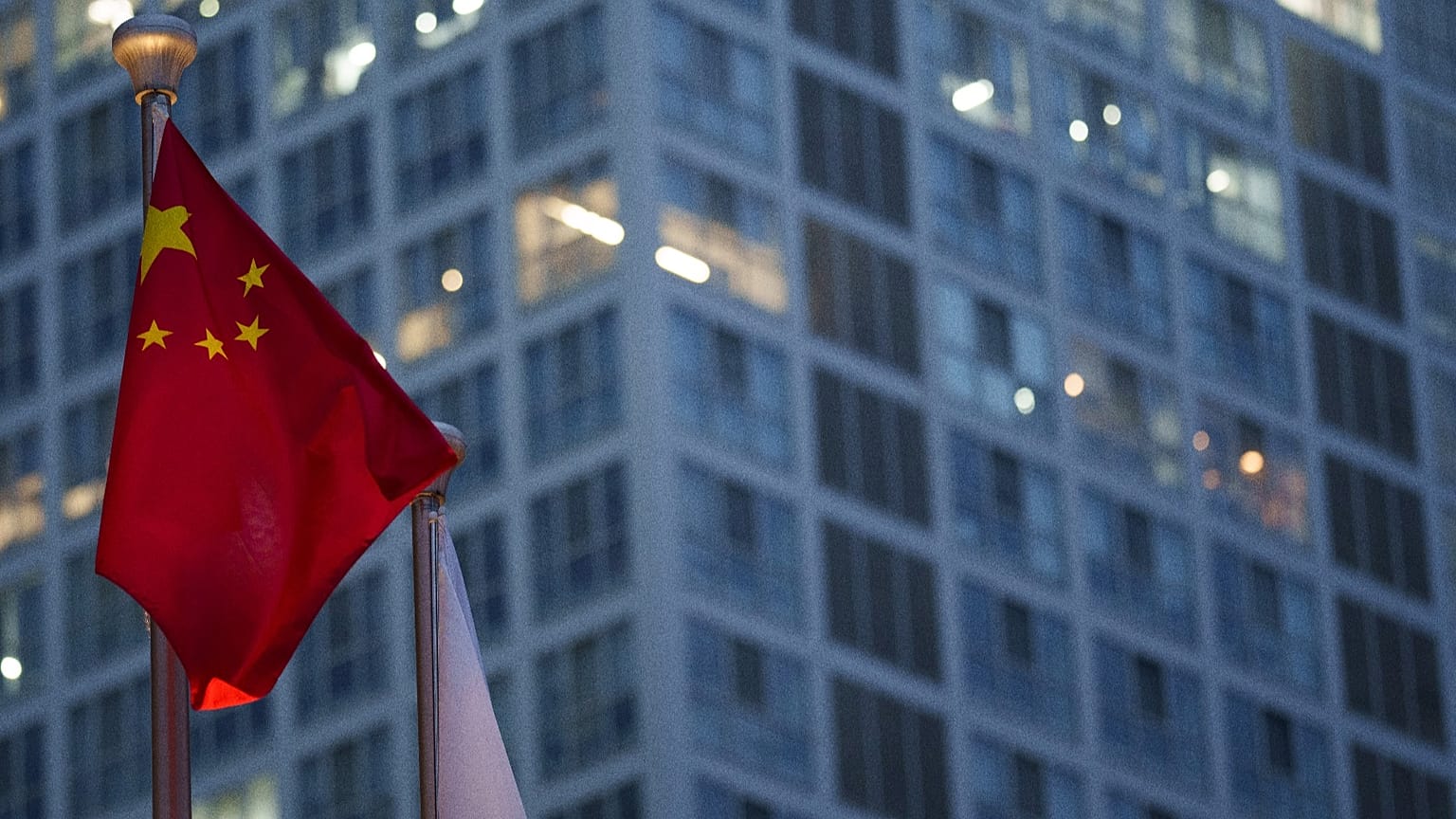 العلم الصيني يرفرف في وقت متأخر من المساء، مع ظهور منطقة الأعمال المركزية في بكين بالصين في الخلفية