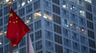 العلم الصيني يرفرف في وقت متأخر من المساء، مع ظهور منطقة الأعمال المركزية في بكين بالصين في الخلفية