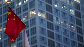 العلم الصيني يرفرف في وقت متأخر من المساء، مع ظهور منطقة الأعمال المركزية في بكين بالصين في الخلفية