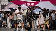 ARCHIV: Eine Frau mit ihren Einkäufen geht an anderen Kundinnen und Kunden vorbei, die sich vor einem Dior-Promostand in Peking versammeln, 17. Aug. 2026