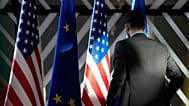 A worker adjusts the US and EU flags at the European Council building in Brussels. 
