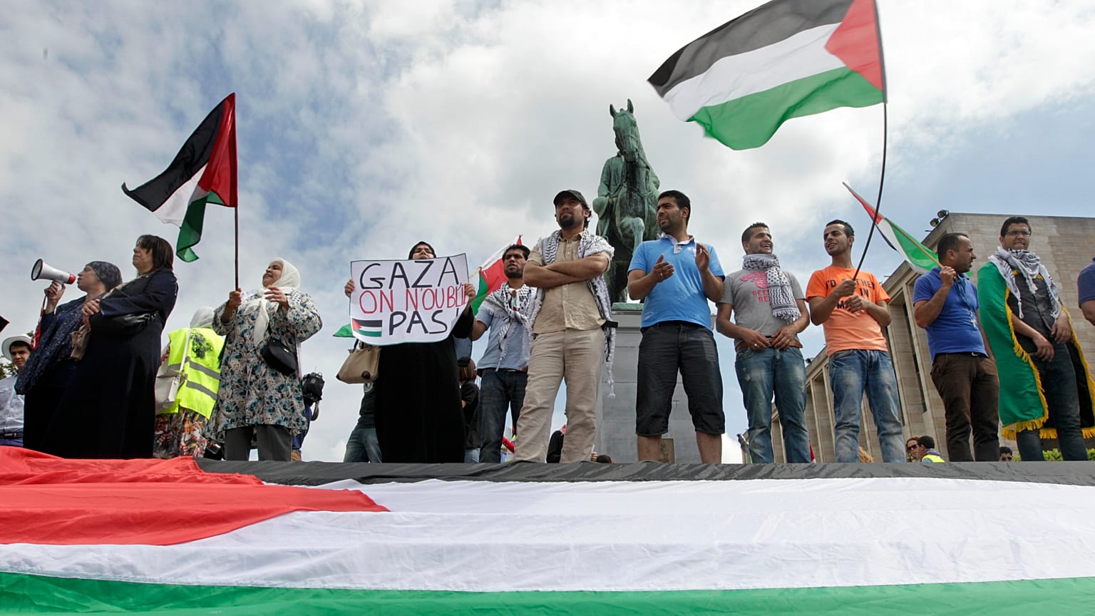 متظاهرون يلوحون بالعلم الفلسطيني خلال مسيرة مؤيدة لفلسطين في بروكسل، يوم الجمعة 25 يوليو/تموز 2014. (صورة من أسوشيتد برس/إيف لوغي)