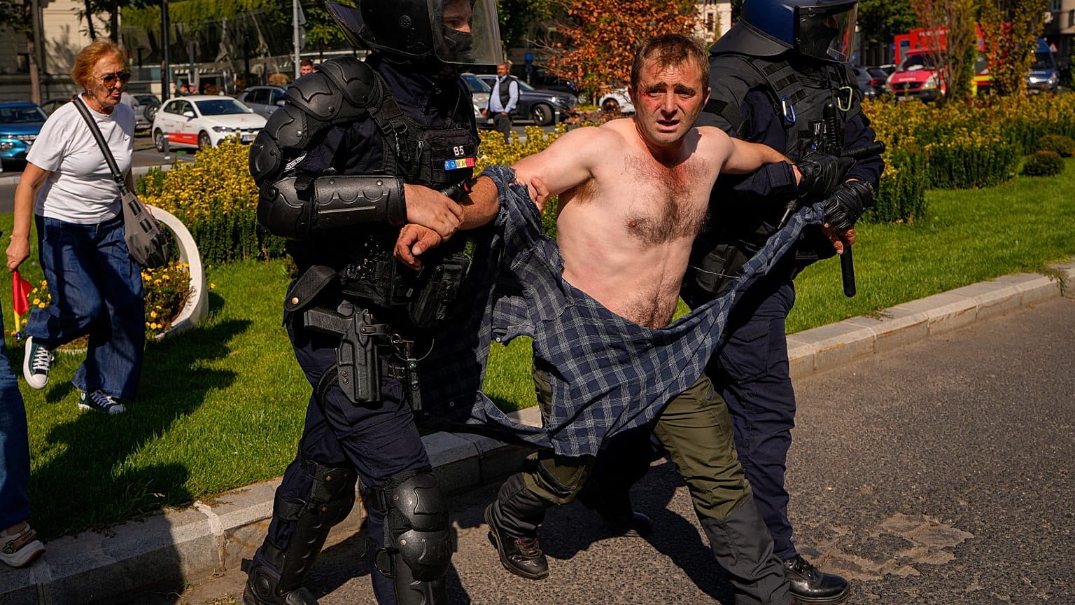 A demonstrator is escorted following scuffles with riot police during a farmers' protest in Bucharest