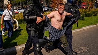 A demonstrator is escorted following scuffles with riot police during a farmers' protest in Bucharest