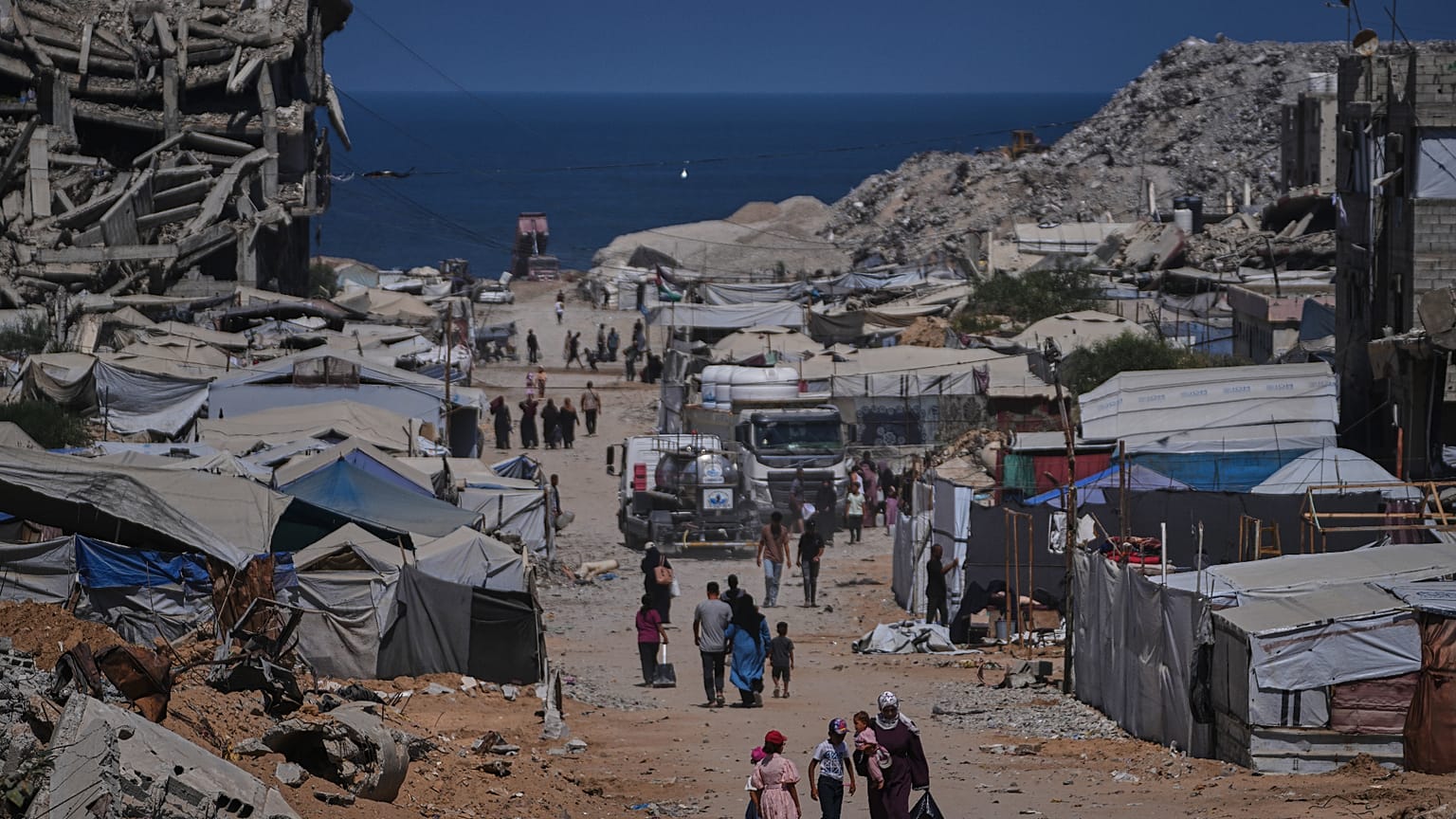 أشخاص يسيرون بمحاذاة خيام تؤوي فلسطينيين نازحين وسط أنقاض مبانٍ دمرتها غارات جوية إسرائيلية خلال الحرب مع حركة حماس، في مدينة غزة، يوم الاثنين 24 أغسطس 2026. (صورة من أسوشيتد 