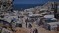 أشخاص يسيرون بمحاذاة خيام تؤوي فلسطينيين نازحين وسط أنقاض مبانٍ دمرتها غارات جوية إسرائيلية خلال الحرب مع حركة حماس، في مدينة غزة، يوم الاثنين 24 أغسطس 2026. (صورة من أسوشيتد 