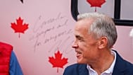 Prime Minister Mark Carney smiles after signing the Forever Canadian bus following a cabinet retreat in Banff, Alta., Friday, Sept. 11, 2026.