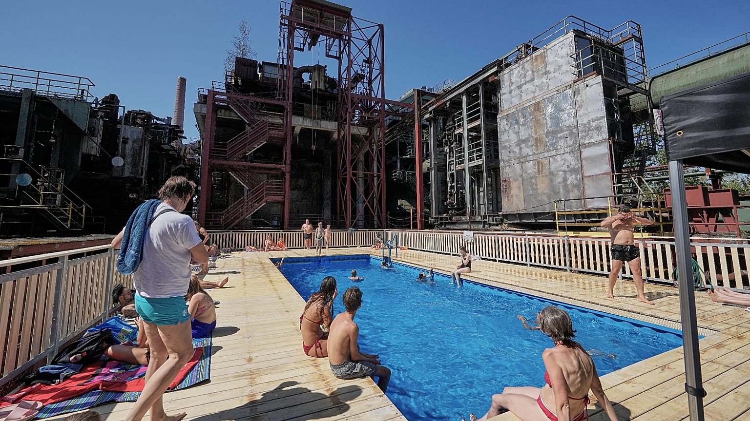 A temporary pool glows blue amidst the industrial backdrop of the world heritage former Zollverein coking plant in Essen, Germany, Friday, Aug. 14, 2026.