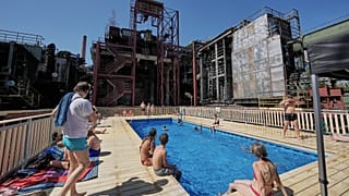 A temporary pool glows blue amidst the industrial backdrop of the world heritage former Zollverein coking plant in Essen, Germany, Friday, Aug. 14, 2026.