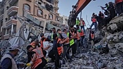 Des équipes de la défense civile palestinienne retirent un corps des décombres d'un immeuble effondré qui abritait des déplacés, endommagé pendant la guerre Israël-Hamas