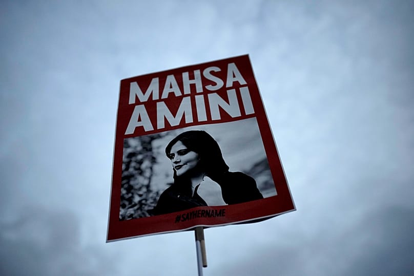  A woman holds a placard with a picture of Iranian woman Mahsa Amini during a protest against her death, in Berlin, Germany, Wednesday, Sept. 28, 2022