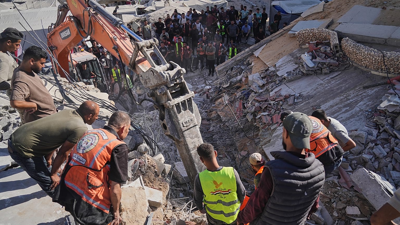 تبحث أطقم الدفاع المدني الفلسطينية عن جثث وناجين تحت أنقاض مبنى منهار كان يؤوي نازحين فلسطينيين وتعرض لأضرار بالغة خلال الحرب الإسرائيلية الحامية