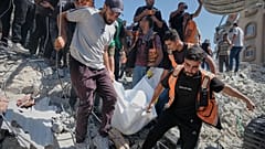 Сотрудники палестинской гражданской обороны выносят тело из-под завалов разрушенного здания, где жили перемещённые палестинцы; оно сильно пострадало в войне Израиля и ХАМАС.