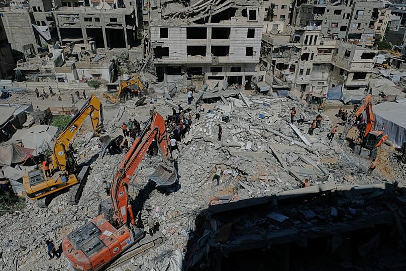 Palestinian civil defense crews search for bodies and survivors in the rubble of a collapsed building that housed displaced Palestinians and was heavily damaged.