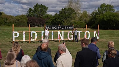 Des habitants dévoilent un panneau "Principauté de Piddington" dans le village de Piddington