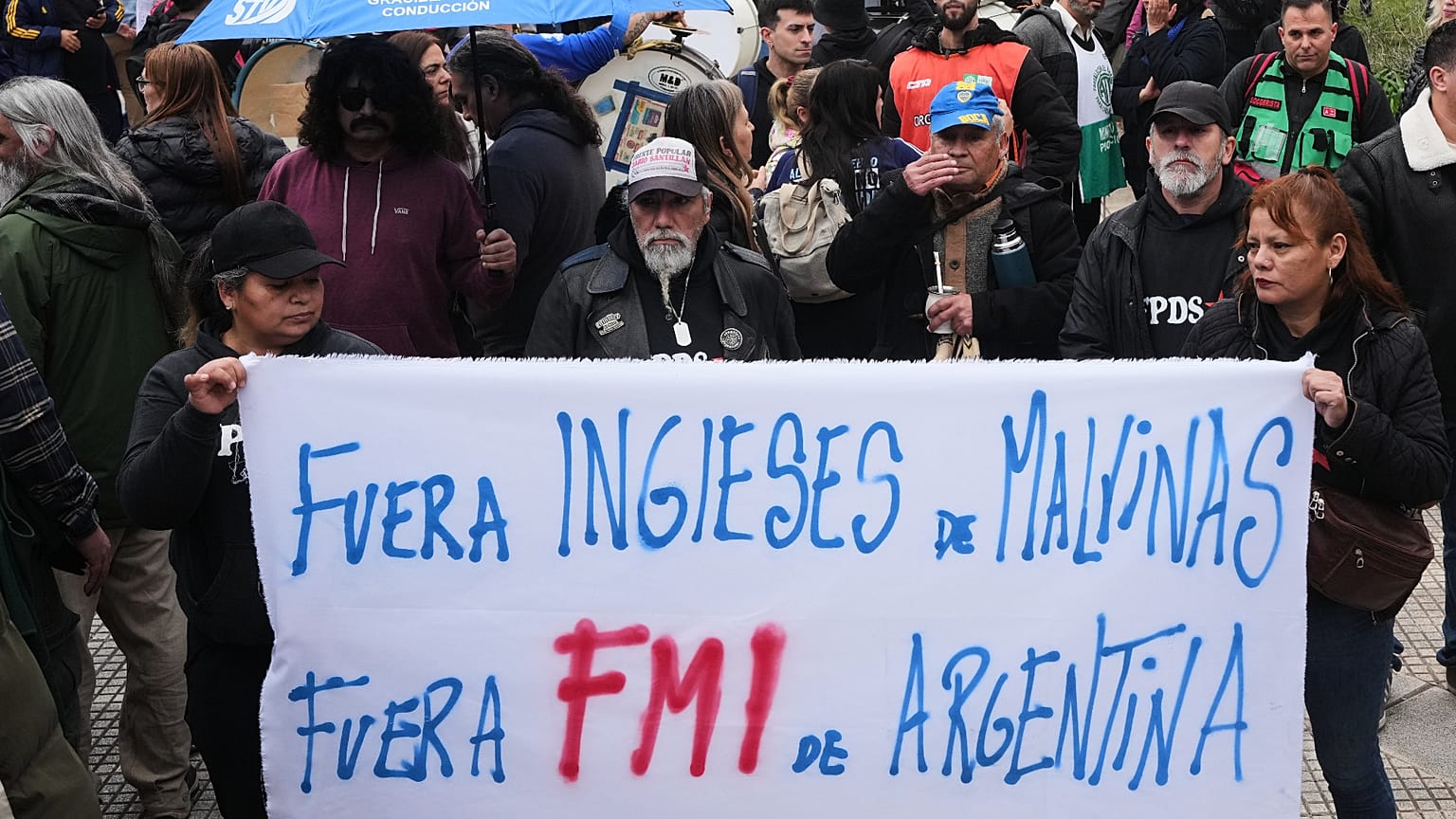 Manifestantes sostienen una pancarta que dice: "Inglés, fuera de Malvinas. FMI fuera de Argentina", frente a la sede del Gobierno durante una reunión 