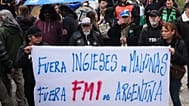 Manifestantes sostienen una pancarta que dice: "Inglés, fuera de Malvinas. FMI fuera de Argentina", frente a la sede del Gobierno durante una reunión 