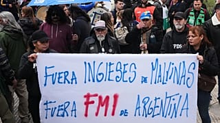 Manifestantes sostienen una pancarta que dice: "Inglés, fuera de Malvinas. FMI fuera de Argentina", frente a la sede del Gobierno durante una reunión 