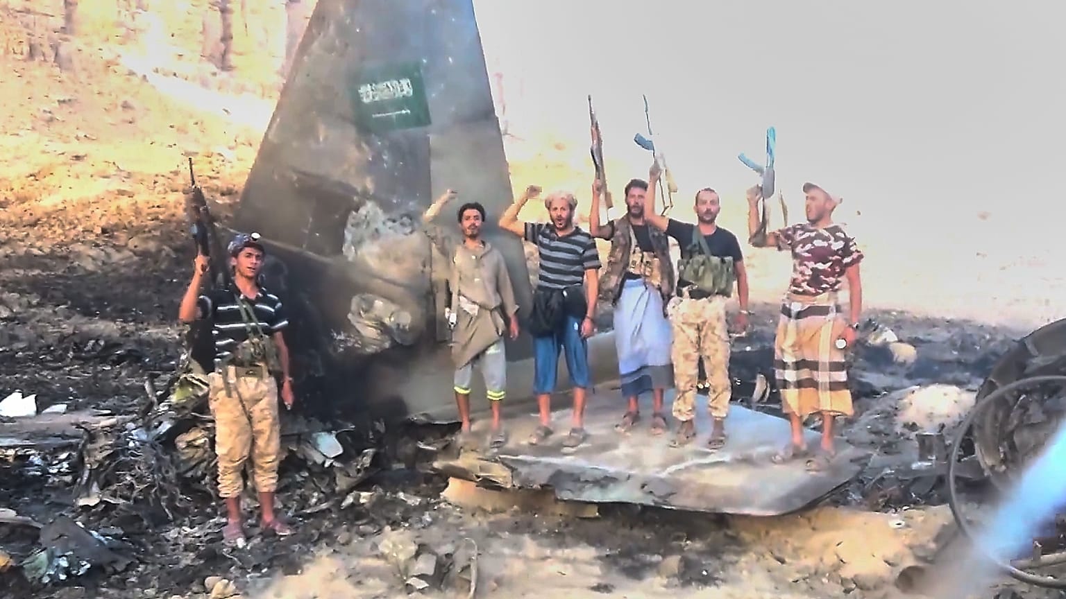 تُظهر هذه الصورة مقاتلين حوثيين يقفون ويهتفون فوق ما وصفته الجماعة بأنه حطام طائرة مقاتلة سعودية من طراز "إف-15" تحمل العلم السعودي