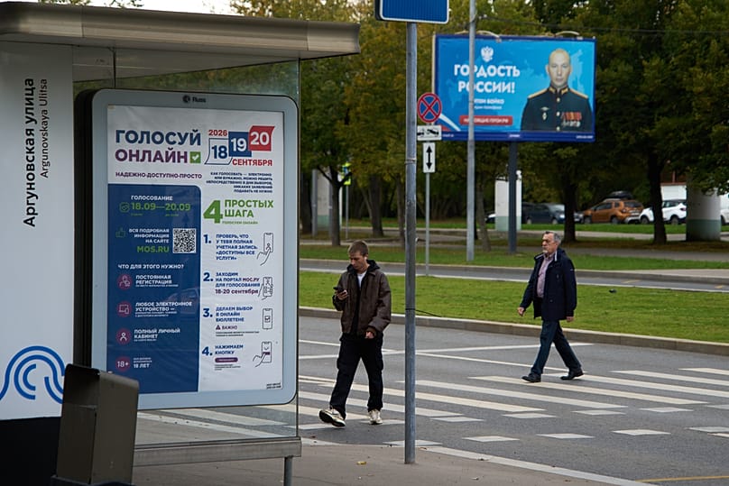 Плакат с рекламой онлайн-голосования на выборах; на заднем плане виден рекламный щит с изображением солдата и надписью «Гордость России». Москва, понедельник, 14 сентября 2026