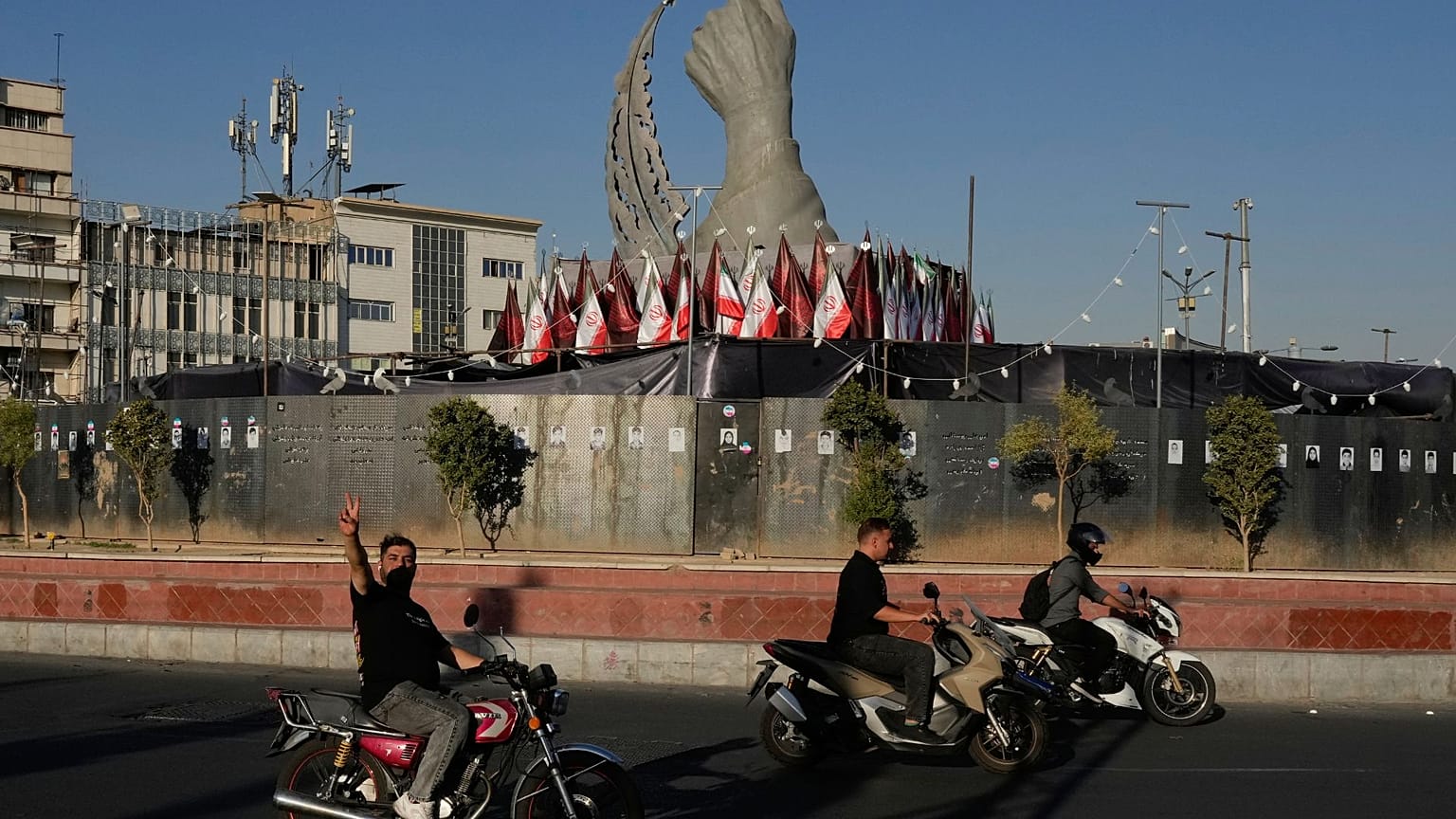 A man reacts to the camera while driving past a monument depicting the clenched fist of the late Iranian Supreme Leader Ayatollah Ali Khamenei, who was killed in the U.S. and 